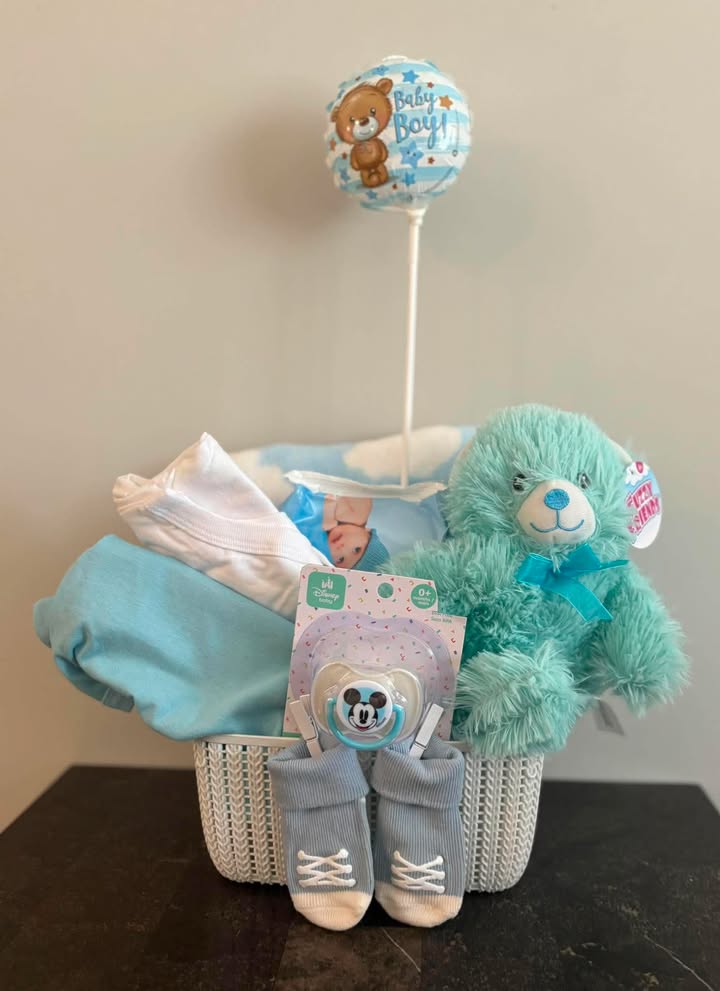 Baby boy basket with blue teddy bear, balloon, pacifier, booties, and clothing