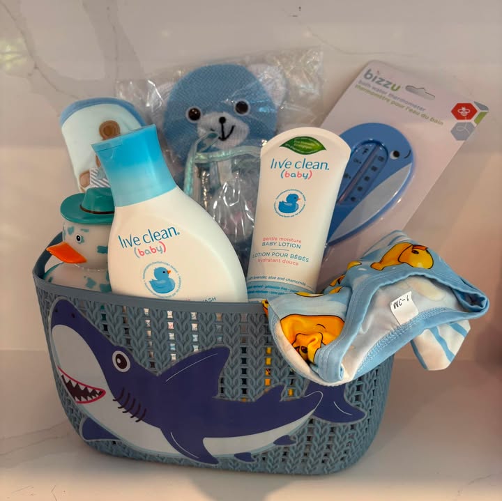 Blue baby basket with shark container, bath items, lotion, and baby clothes