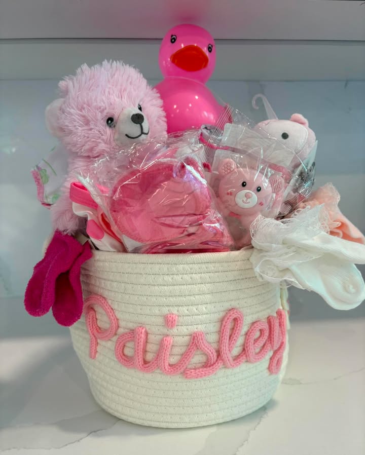 Personalized pink baby basket with toys, teddy bear, clothing, and bath items